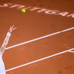 Tenisistka serwuje podczas turnieju w Stuttgarcie. Piłka w locie, kort ziemny.