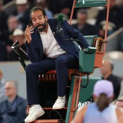 Sędziowie tenisa ziemnego WTA w akcji. Sędzia na krześle z mikrofonem, gestykuluje do gracza.