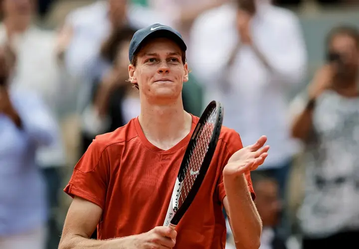 Tenisista w pomarańczowej koszulce i czapce z daszkiem, z rakietą w dłoni, dziękuje publiczności po meczu ATP 250.
