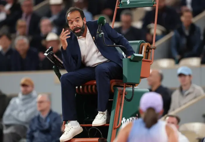 Sędziowie tenisa ziemnego WTA w akcji. Sędzia na krześle z mikrofonem, gestykuluje do gracza.