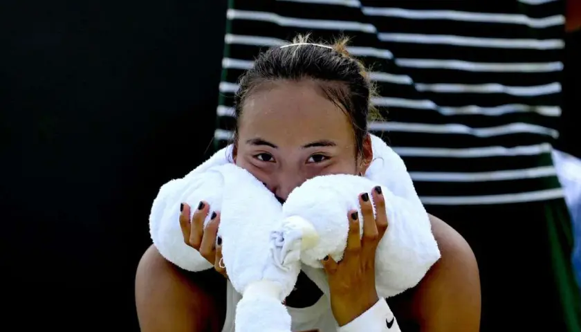 Zmęczona zawodniczka zheng tennis wyciera twarz ręcznikiem.