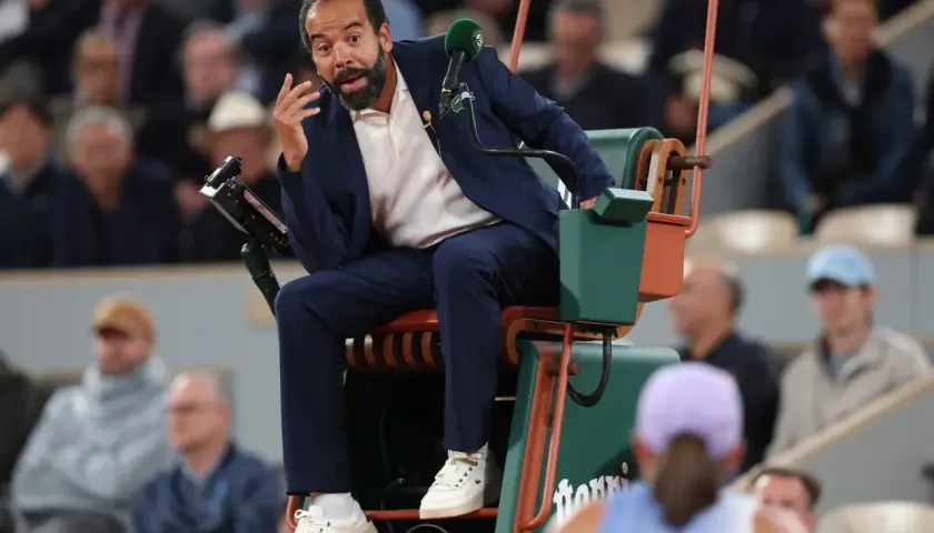 Sędziowie tenisa ziemnego WTA w akcji. Sędzia na krześle z mikrofonem, gestykuluje do gracza.