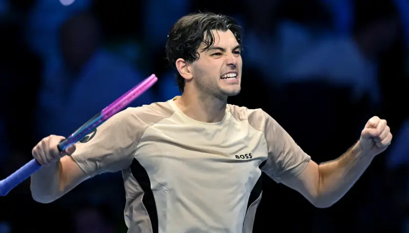 Taylor Fritz, tenisista, triumfuje po wygranym punkcie, zaciskając pięść i unosząc rakietę.