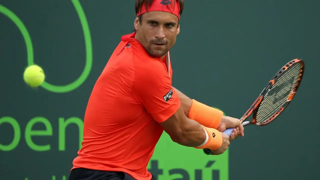 David Ferrer w akcji, uderza piłkę rakietą. Intensywny pomarańczowy strój i opaski na nadgarstkach.